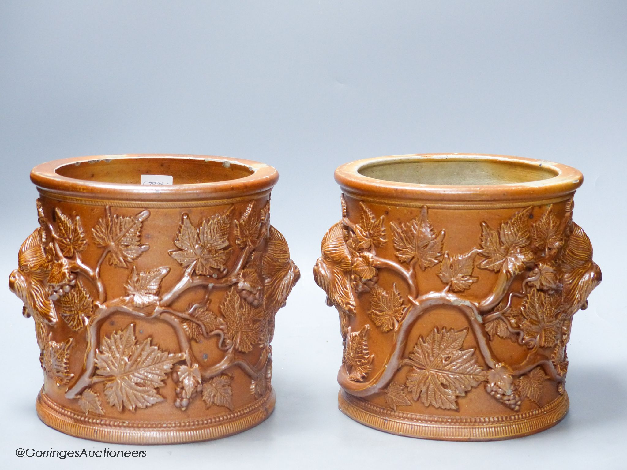 A pair of early 19th century salt glazed stoneware cylindrical pots, relief moulded with grapes and vine leaves